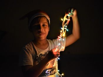 Portrait of happy girl holding illuminated lighting equipment