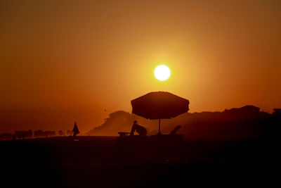 Scenic view of silhouette mountains against orange sky