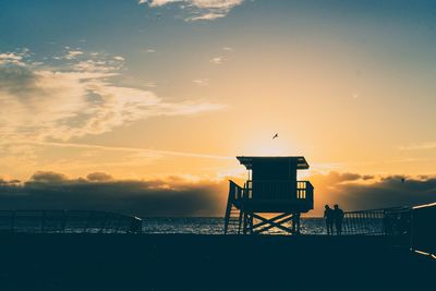 Lifeguard hut on beach against sky during sunset