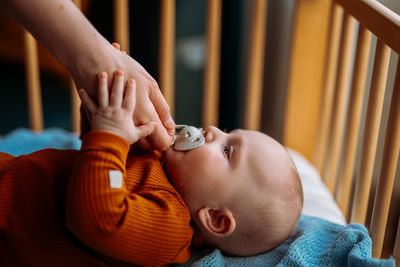 Cute baby with mouthpiece in crib