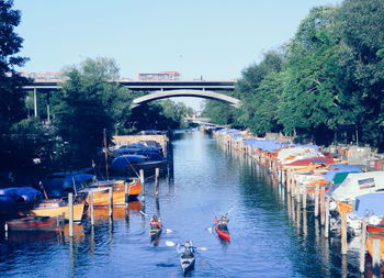 People on bridge over river against sky