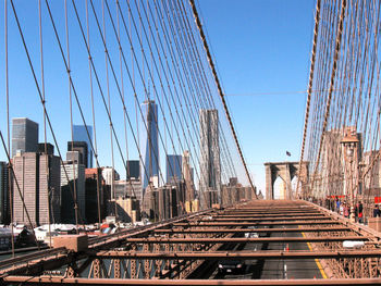 Suspension bridge in city against clear blue sky