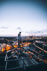 Man standing by illuminated cityscape against sky