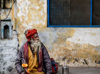 Sadhu sitting on sidewalk against house