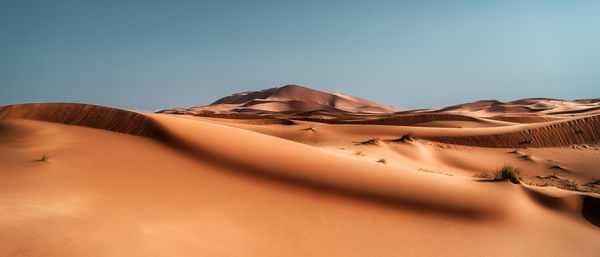 Sand dunes in desert against clear sky