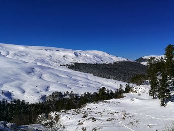 Scenic view of snowcapped mountains against clear blue sky