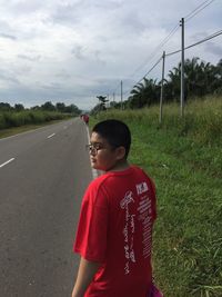 Boy standing on grass against sky