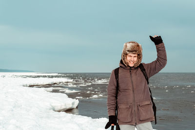 Portrait of man standing on frozen lake against clear sky