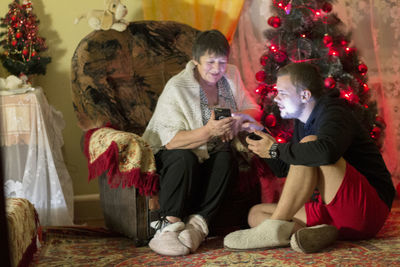 People sitting by christmas tree