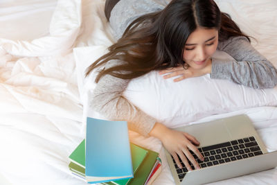 High angle view of woman using laptop on bed at home