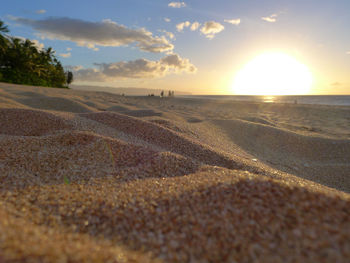Surface level of beach against sky during sunset