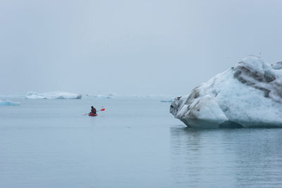 Floating icebergs and a kayaker in jokulsarlon glacial lagoon, iceland. global warming