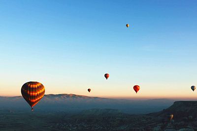 Hot air balloons flying over landscape against clear sky