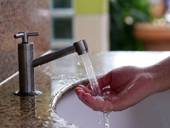 Close-up of hand holding water from faucet