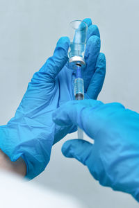 Cropped hands of doctor holding syringe with vial at hospital