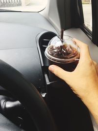Cropped hand having drink in car
