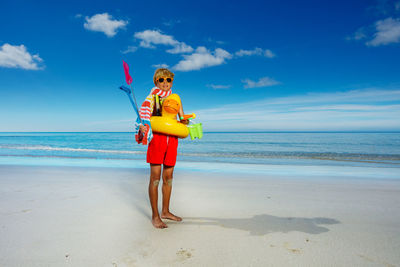 Full length of woman standing at beach against sky