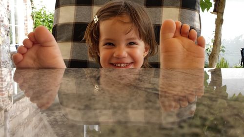 Close-up of cute girl sitting on chair with feet up on table