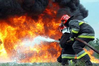 Low angle view of firefighters spraying water on fire