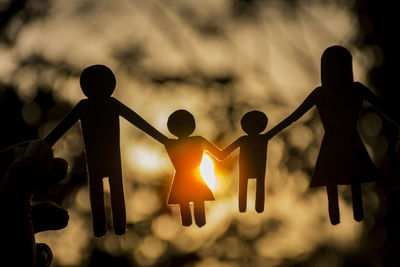 Close-up of silhouette paper chain during sunset