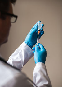 Doctor in white coat drawing vaccine into a syringe for injection.