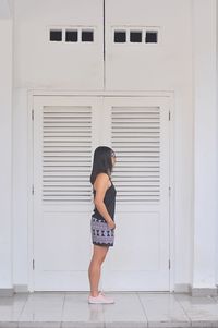 Side view of woman standing by building in city