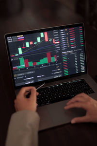 High angle of crop anonymous trader using netbook while analyzing chart on binary option
