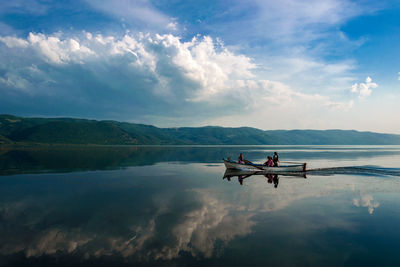 People in boat on lake against sky