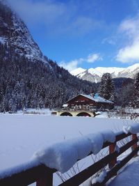 Snow covered houses by mountain against sky