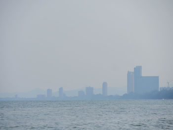 Sea by buildings against clear sky