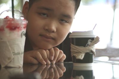 Portrait of boy looking though disposable glasses on table