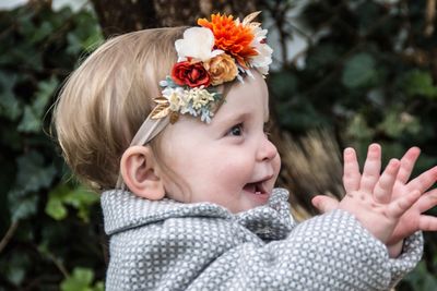 Cute baby girl applauding while wearing flower headband