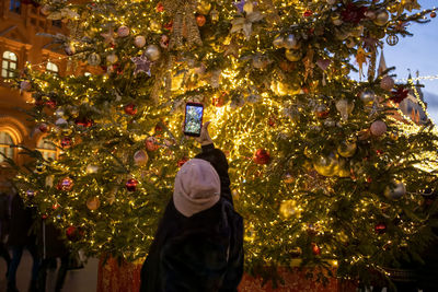 Rear view of woman standing by christmas tree