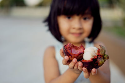 Close-up portrait of girl holding mangosteen