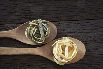 Close-up of tagliatelle pasta in wooden spoons on table