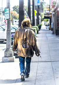 Rear view of homeless person walking on sidewalk