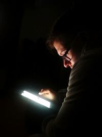 Midsection of man using mobile phone at night