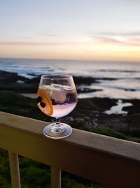 Close-up of gin on table against sky during sunset