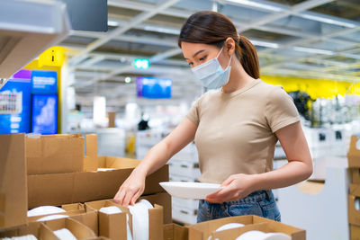 Young woman holding camera while standing in box