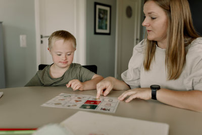 Mother teaching son with down syndrome at home