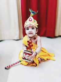 Portrait of boy with toy sitting on floor at home