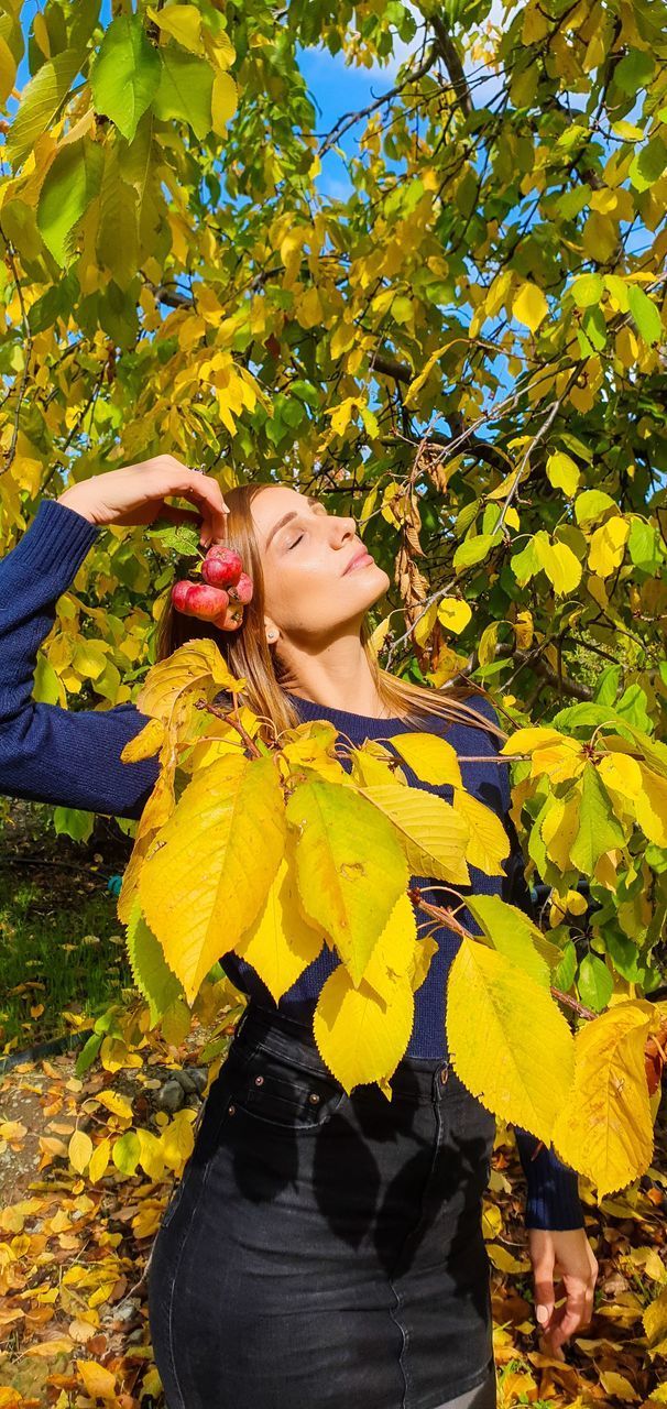 YOUNG WOMAN WITH YELLOW LEAVES AND PLANTS