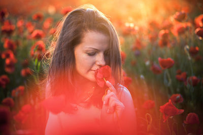 Close-up of young woman with poppy flowers