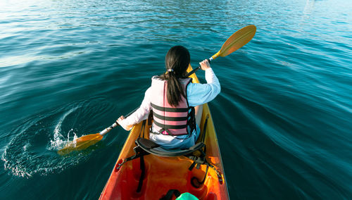 Rear view of woman holding boat in sea