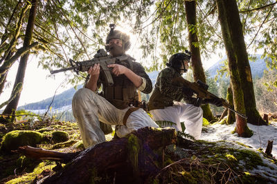 Young man sitting on tree trunk in forest