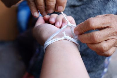 Midsection of person tying string in woman hand