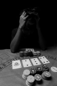 Man with head in hands gambling against black background