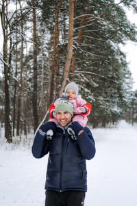 Portrait of happy father and baby toddler daughter on winter nature background. man and baby girl