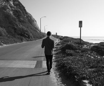 Rear view of woman standing on road