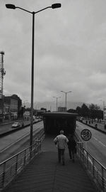 Rear view of people walking on street against sky